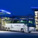 Ein Reisebus steht auf dem Firmengelände der Auto Bachem GmbH. Das Firmengebäude im Hintergrund ist beleuchtet.