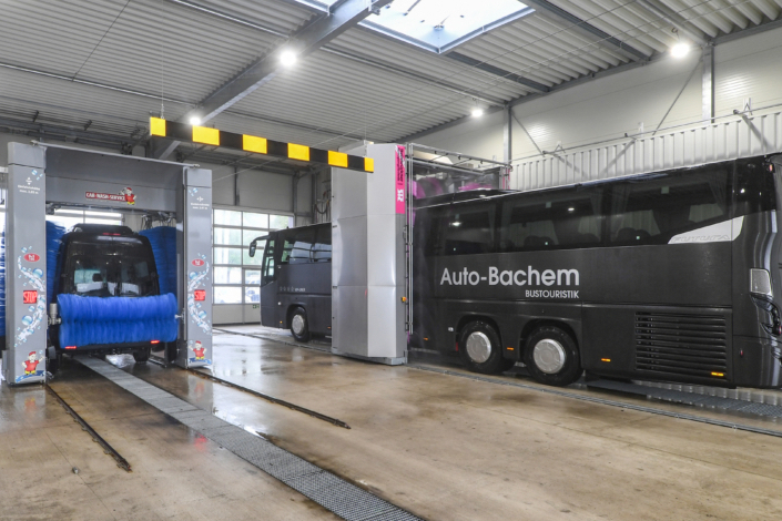 XXL-Waschanlage Ein Bus wird in einer Garage gewaschen, während Wasser und Seife auf die Karosserie gesprüht werden.